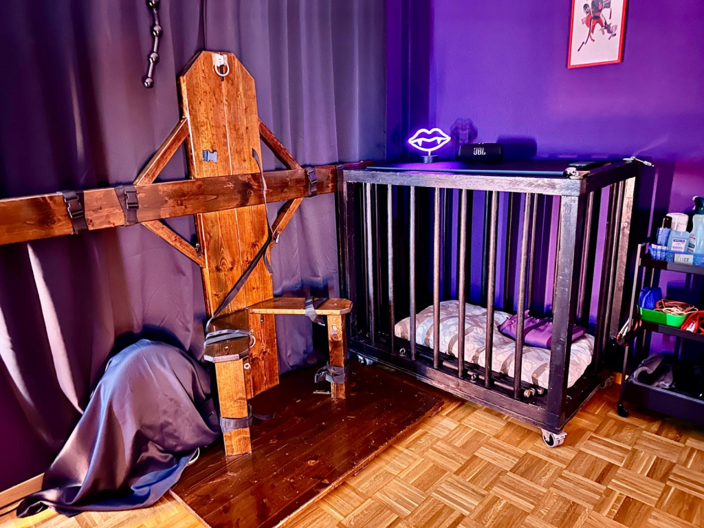Siège de contention en bois et cage à barreaux dans la salle de jeu du donjon privé à Lausanne